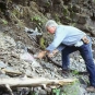 Photographie couleur d’un homme se penchant pour ramasser des roches