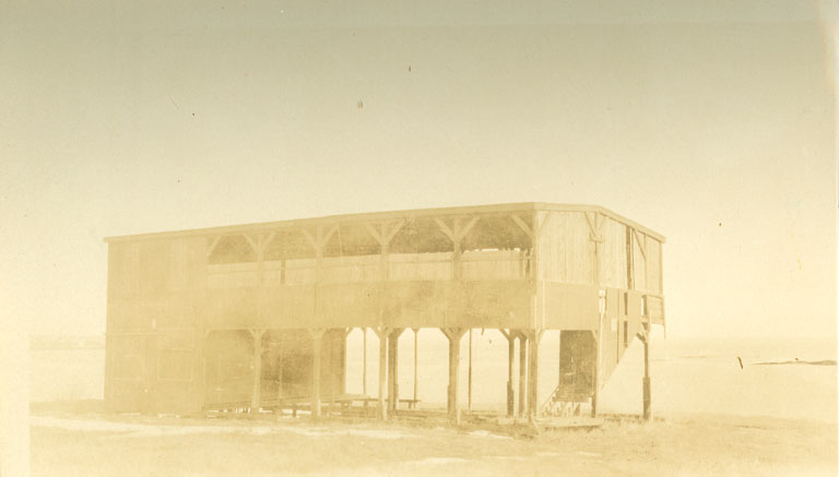 Photographie noir et blanc d’un ancien bâtiment en bois de deux étages
