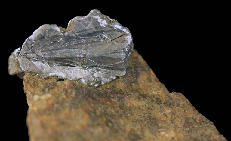 Colour image of brown rock with top tip of gray rock with high sheen