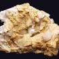 Colour image of yellow rock with multiple jagged edges and round chunks of white rock
