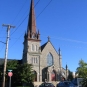 Photographie couleur d’une église en pierre dotée d’un grand clocher sur la gauche