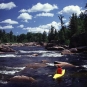 Photographie couleur montrant une personne en kayak jaune dans des rapides