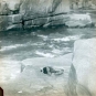 Image couleur d’une rivière et d’une ligne de rivage rocheuse et d’un homme glissé dans un trou laissant voir seulement sa tête et ses pieds