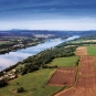 Colour photograph of a river with green fields on both sides