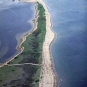 Colour photograph of a sand bar with green plants on it and with ocean both sides