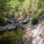 Colour photograph of stream, rocky outcrop and trees