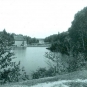 Black and white photograph of a lake and trees with and old wooden building